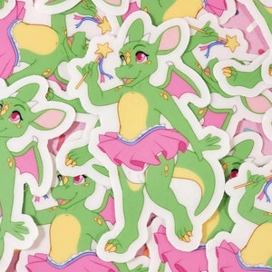 May include: A green dragon wearing a pink tutu and holding a wand with a star on top. The dragon has pink eyes and gold scales. The background is white.