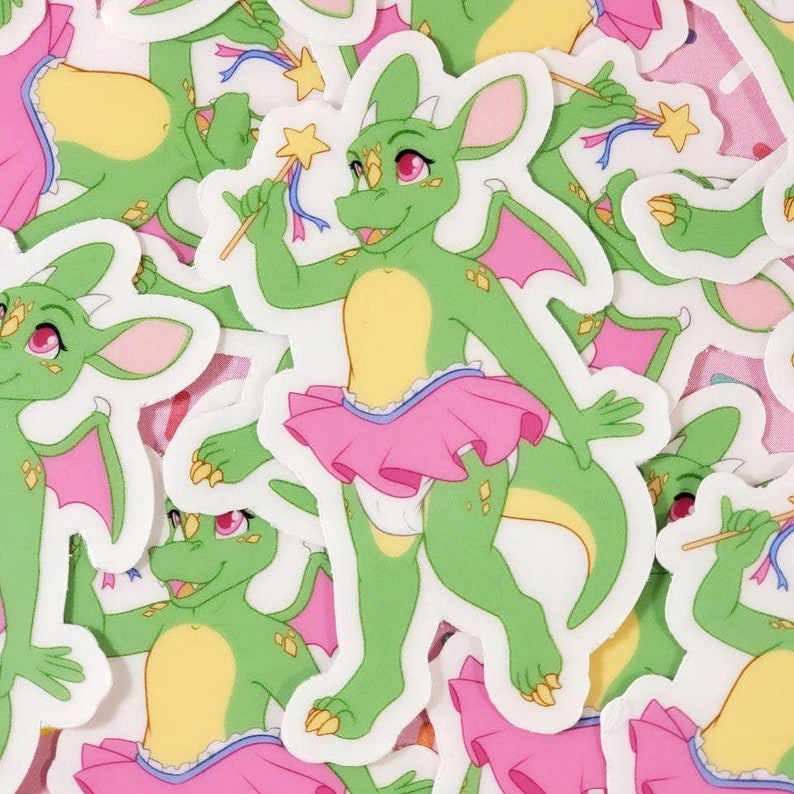 May include: A green dragon wearing a pink tutu and holding a wand with a star on top. The dragon has pink eyes and gold scales. The background is white.