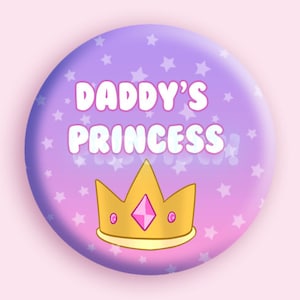 May include: A purple and pink button with a crown and the text "Daddy's Princess" in white.