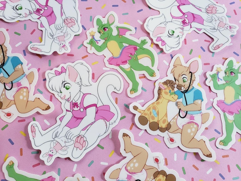 May include: A collection of colorful stickers featuring various cartoon animals wearing pink dresses and diapers. The stickers are on a pink background with white sprinkles.
