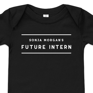 May include: Black baby onesie with white text that reads "SONJA MORGAN'S FUTURE INTERN".