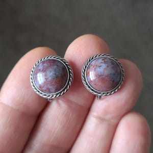 May include: A pair of silver clip-on earrings with round, red, white, and gray agate stones.