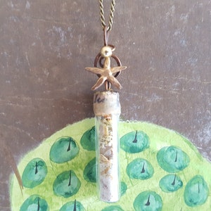 May include: A gold-toned necklace with a glass vial pendant filled with sand and a gold starfish charm.