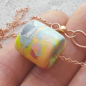 brightly coloured neon polymer clay bead, It has multiple pastel and neon colors of coral, peach,, pink,, lime green, yellow, blue, grey and lavender on chain with hook clasp