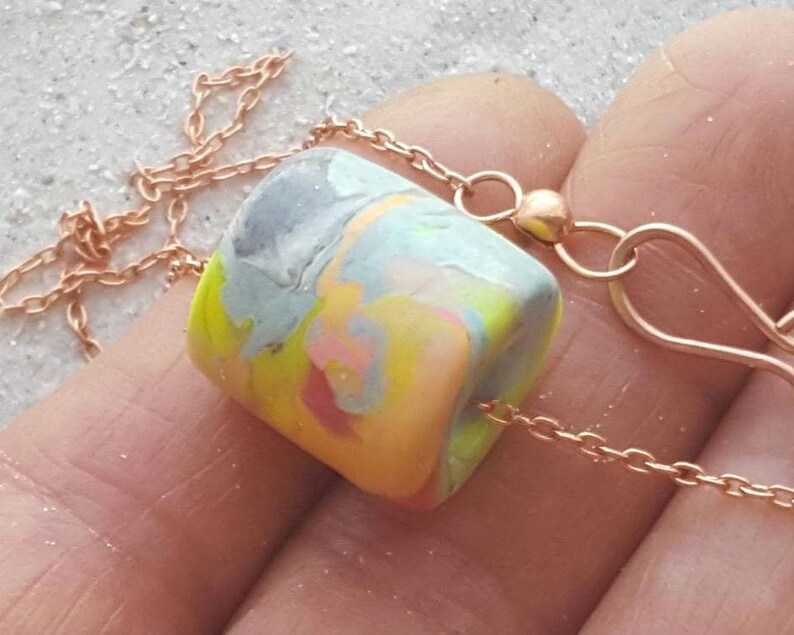 brightly coloured neon polymer clay bead, It has multiple pastel and neon colors of coral, peach,, pink,, lime green, yellow, blue, grey and lavender on chain with hook clasp