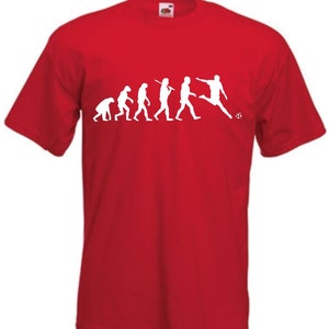 May include: Red t-shirt with a white graphic depicting the evolution of a footballer, from early hominids to a player kicking a ball. The shirt has short sleeves and is made of a soft fabric.