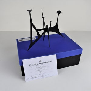 May include: A black metal sculpture on a blue box with a certificate of authenticity. The certificate reads "David  Fernandez, Stable  Univa 01,  Paris 14 octobre 2011."