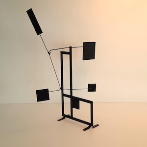 Peut inclure: Sculpture mobile en métal noir avec des formes géométriques et une base rectangulaire.