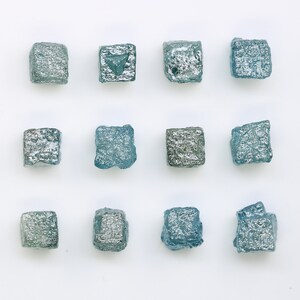 May include: Twelve small, square, blue and silver metallic tiles arranged in a grid pattern on a white background.