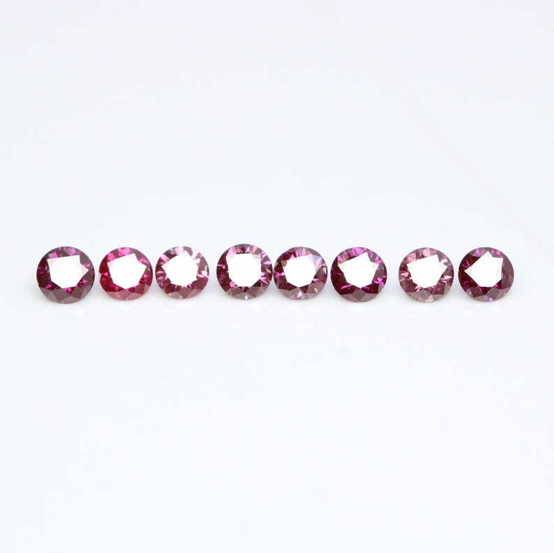 May include: Eight round, faceted gemstones in a row. The gemstones are a deep pink color with a slight purple hue.