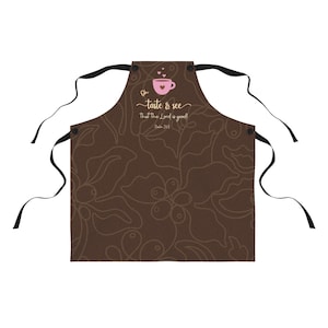 May include: Brown kitchen apron with a coffee cup design and the text "Oh taste & see that the Lord is good! Psalm 34:8".