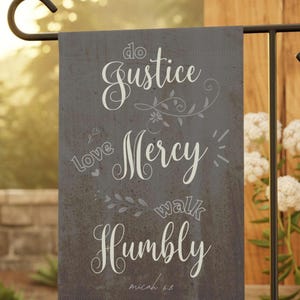 Peut inclure: Un drapeau de jardin gris avec du texte blanc qui dit "Do Justice, Love Mercy, Walk Humbly, Micah 6:8". Le drapeau a un aspect rustique et vieilli et présente des motifs floraux.