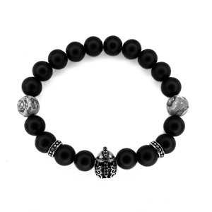 Peut inclure: Bracelet en perles noires avec un charme de casque argenté et deux perles d'agate grises.