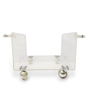 May include: A clear acrylic rolling cart with a U-shaped design. The cart has two clear handles and four silver-colored ball-shaped wheels. The cart is designed to hold items and move them easily.