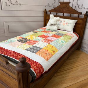 May include: A miniature wooden bed with a patchwork quilt in various colors, including red, yellow, and green. A white pillow with floral embroidery and a stuffed bunny are on the bed. The bed frame is a dark wood.