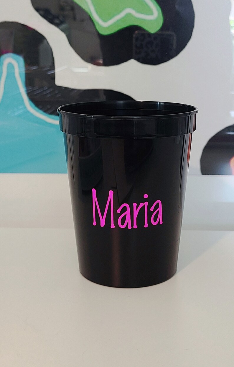 May include: A black plastic cup with the name "Maria" written in pink letters.