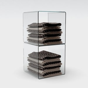 May include: Two clear acrylic storage boxes stacked on top of each other. Each box contains a stack of folded fabric with a brown and white geometric pattern.