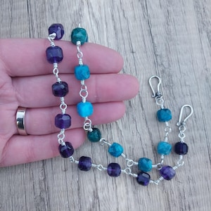 May include: A silver chain necklace with alternating amethyst and turquoise gemstone beads. The beads are faceted and have a square shape.