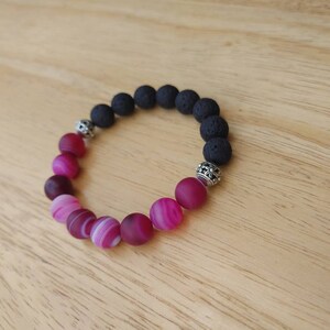 May include: A pink and white agate gemstone bracelet with black lava rock beads and silver spacers.
