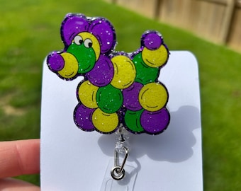 May include: A purple, green, and yellow glitter balloon animal shaped like a dog with a clear plastic retractable badge holder.