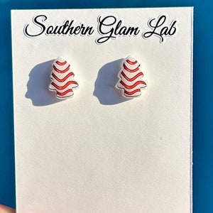 May include: A pair of red and white striped Christmas tree stud earrings on a white card with the text "Southern Glam Lab".