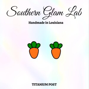 May include: A pair of carrot-shaped earrings with green tops and orange bodies. The earrings are made with titanium posts.
