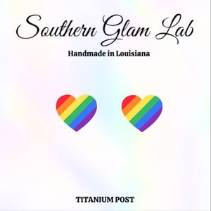 May include: A pair of rainbow heart-shaped earrings with a titanium post. The earrings are handmade in Louisiana. Southern Glam Lab.