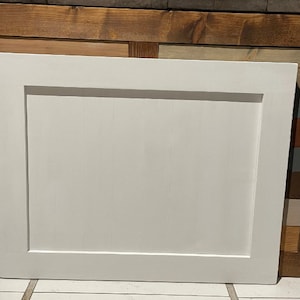 May include: White framed rectangular panel with a smooth, white surface. The panel has a raised border around the edges.