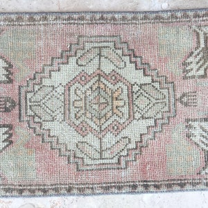 May include: A vintage pink and beige runner rug with a geometric pattern. The rug has a faded look and is made of a woven material.