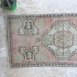 May include: A vintage pink and gray patterned rug with a fringed edge. The rug has a geometric design with a central medallion.