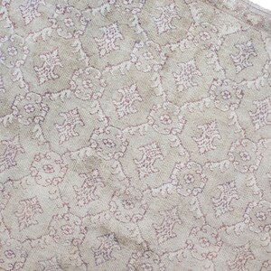 May include: A vintage rug with a cream background and a repeating pattern of pink floral designs.