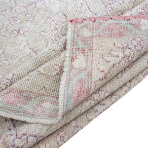 May include: A folded vintage rug with a cream background and a faded pink and blue floral pattern.