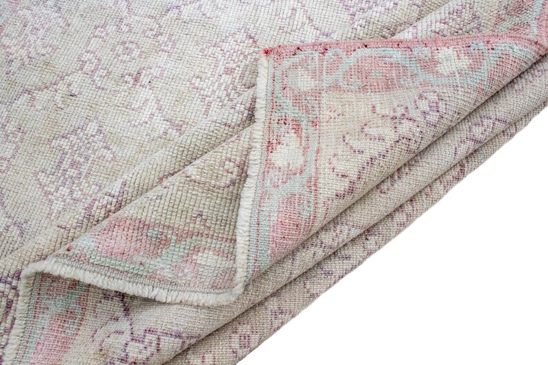 May include: A folded vintage rug with a cream background and a faded pink and blue floral pattern.