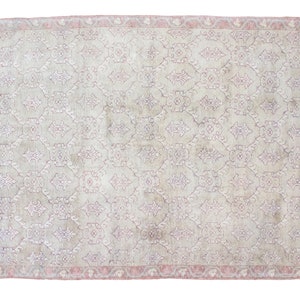 May include: A vintage rug with a light beige background and a delicate floral pattern in shades of pink and purple. The rug has a pink border.