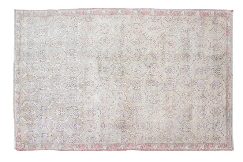 May include: A vintage rug with a light beige background and a delicate floral pattern in shades of pink and purple. The rug has a pink border.