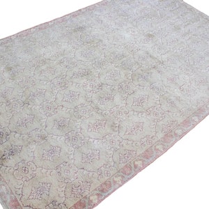 May include: A vintage rug with a light beige background and a delicate pink floral pattern. The rug has a faded, distressed look, giving it a unique and antique feel.