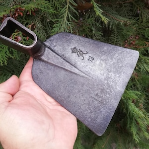 May include: A black metal hand tool with a wooden handle. The tool has a sharp blade and a curved head. The tool is used for digging and gardening.