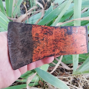 Puede incluir: Una cabeza de hacha oxidada, naranja y negra con el texto "SANDVIK" y "010" impreso en el lado naranja.
