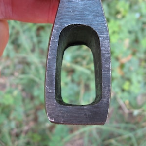 May include: Close-up of the eye of an axe head. The eye is a rectangular opening in the metal, designed to hold the handle.