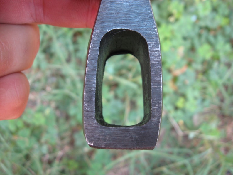 May include: Close-up of the eye of an axe head. The eye is a rectangular opening in the metal, designed to hold the handle.