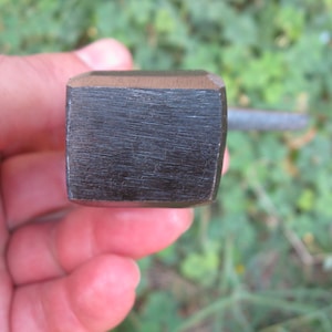 May include: Close-up of a black metal wrench with a square head.