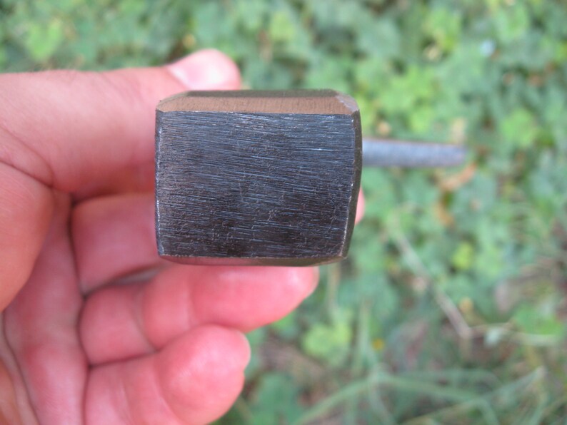 May include: Close-up of a black metal wrench with a square head.