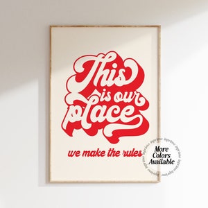 May include: Red and white typography print with the text "This is our place we make the rules". The text is in a bold, stylized font. The print has a white background and is framed in a light wood frame.