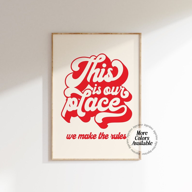May include: Red and white typography print with the text "This is our place we make the rules". The text is in a bold, stylized font. The print has a white background and is framed in a light wood frame.