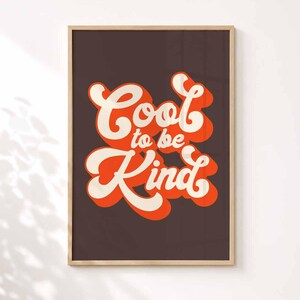Puede incluir: Una l&aacute;mina decorativa rectangular en un marco de madera clara con el texto Cool to be Kind en una tipograf&iacute;a de color crema con una sombra naranja intensa. Las letras se sit&uacute;an sobre un fondo marr&oacute;n oscuro s&oacute;lido de alto contraste.
