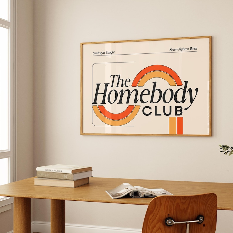 以下が含まれることがあります： オレンジ、赤、黄色の虹の弧を持つ黒い「The Homebody Club」というテキストを特徴とするレトロなデザインの額装されたプリント。プリントの上部には、「Staying In Tonight」と「Seven Nights a Week」というテキストが黒で印刷されています。