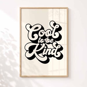K&ouml;nnte beinhalten: Ein rechteckiger Wandkunstdruck in einem hellen Holzrahmen mit dem schwarzen Schriftzug Cool to be Kind in einer fetten, retro-inspirierten Schriftart mit Schlagschatteneffekt. Der Schriftzug ist auf einem cremefarbenen Hintergrund zentriert.