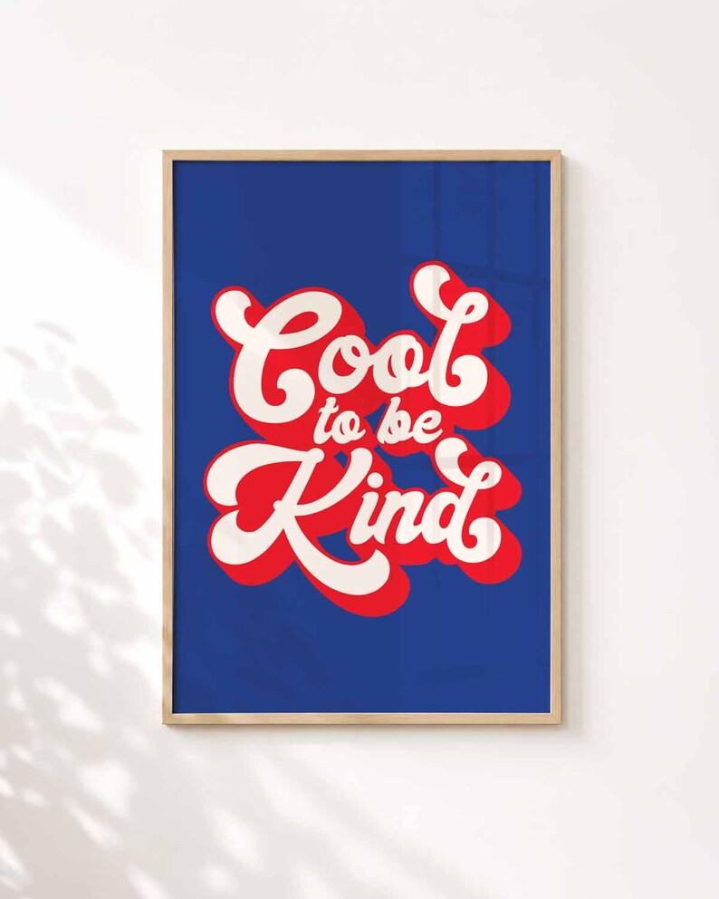 Puede incluir: Una pieza de arte mural rectangular enmarcada con un fondo azul profundo y el texto Cool to be Kind escrito en una fuente blanca audaz de estilo retro. Las letras tienen una sombra roja gruesa, creando un efecto de capas dentro del marco de madera clara.
