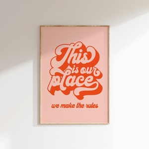 May include: A pink framed print with the text "This is our place we make the rules" in orange and white lettering.