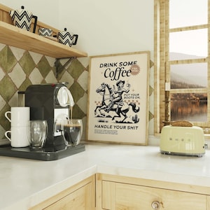 Cowgirl-inspired wall art print that says “Drink Some Coffee, Put Your Boots On, Handle Your Sh*t,” styled for a modern coffee bar or kitchen coffee station with a warm western vibe and motivational decor.